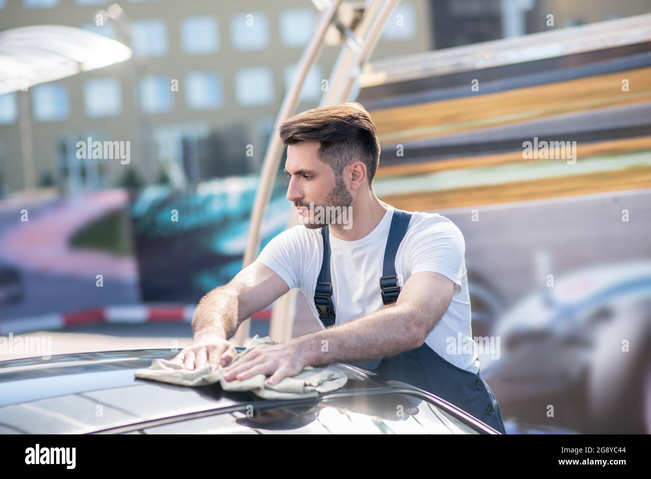 Profil von schweren jungen Mann wischen Auto Stockfoto