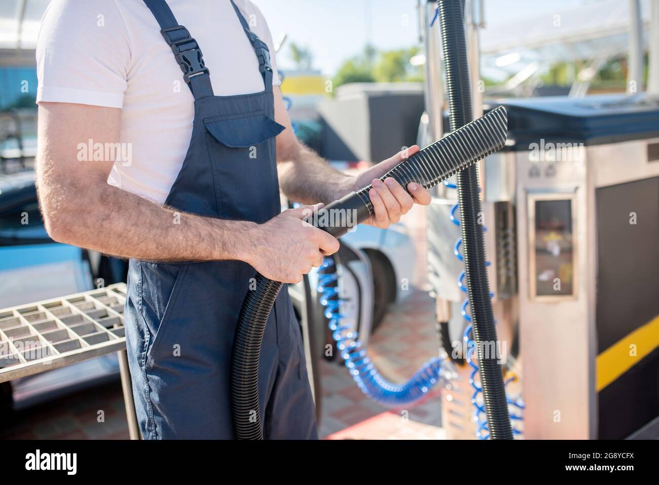 Mann mit Rohr des Staubsaugers bei der Autowäsche Stockfoto