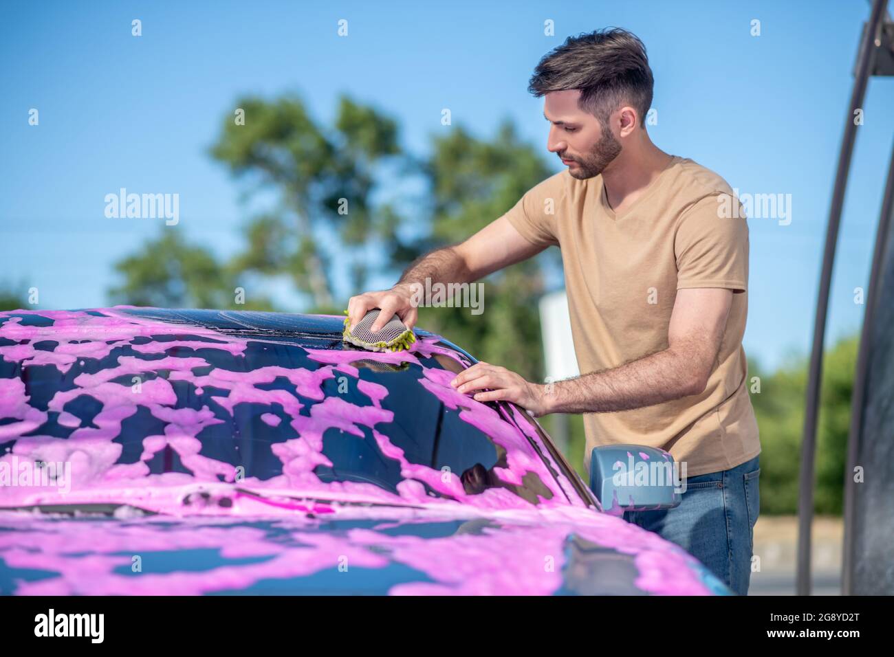 Profil eines Mannes, der Schaum mit Serviette auf dem Auto wischte Stockfoto
