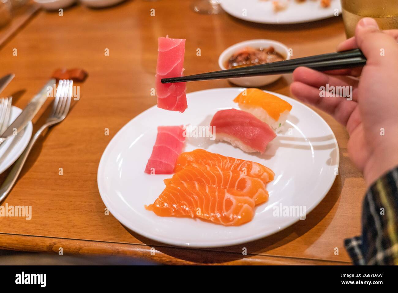 Frau, die Sashimi mit Essstäbchen isst Stockfoto