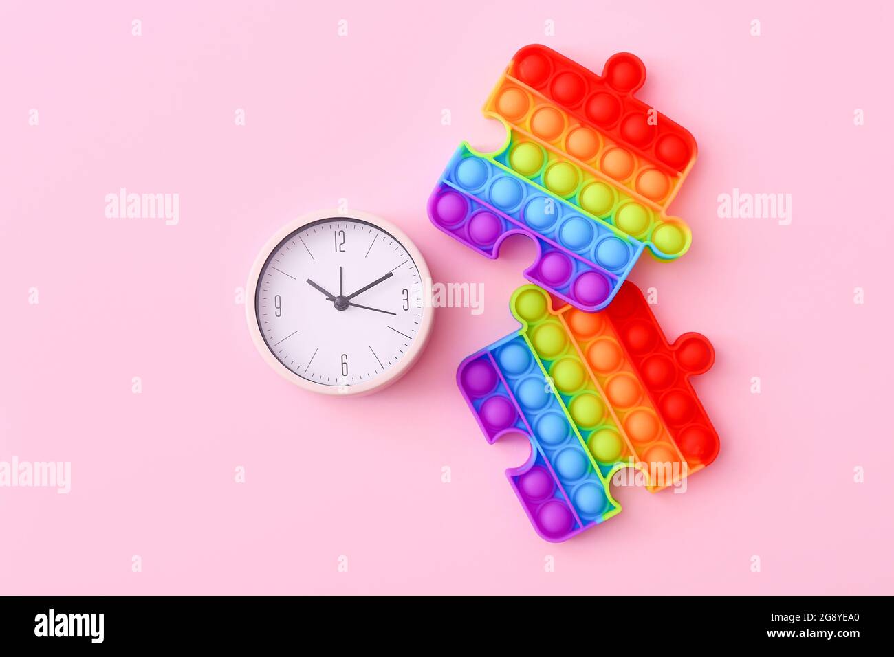 Farbenfrohe Antistress-Sinnesspielzeug mit Uhr auf rosa Hintergrund, Draufsicht Stockfoto
