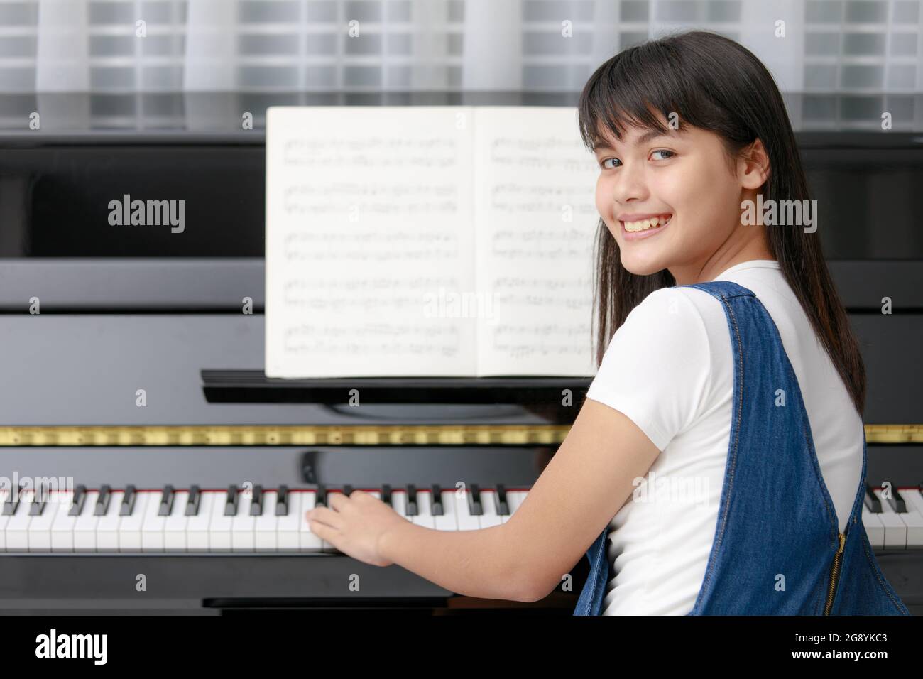 Junge ziemlich schöne asiatische Mädchen am Klavier mit verwackelte Noten  und Metronom, die Rhythmus-Ausrüstung sitzen Stockfotografie - Alamy