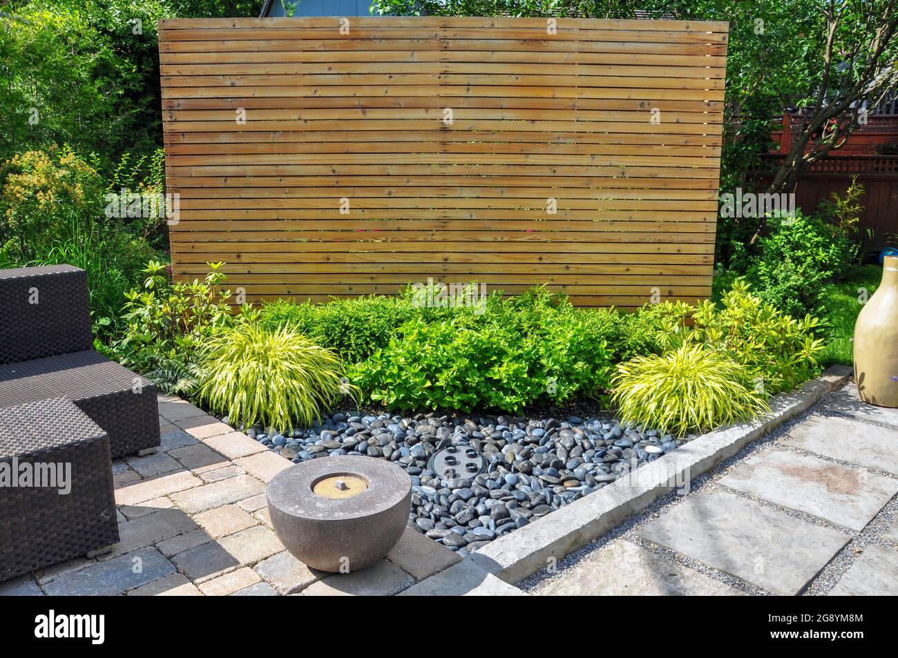 Strandkiesel, quadratische Steinplatten, tropfende Pflastersteine und einfache Pflanzungen sorgen in diesem kleinen, modernen Garten im Hinterhof für Textur und Kontrast. Stockfoto