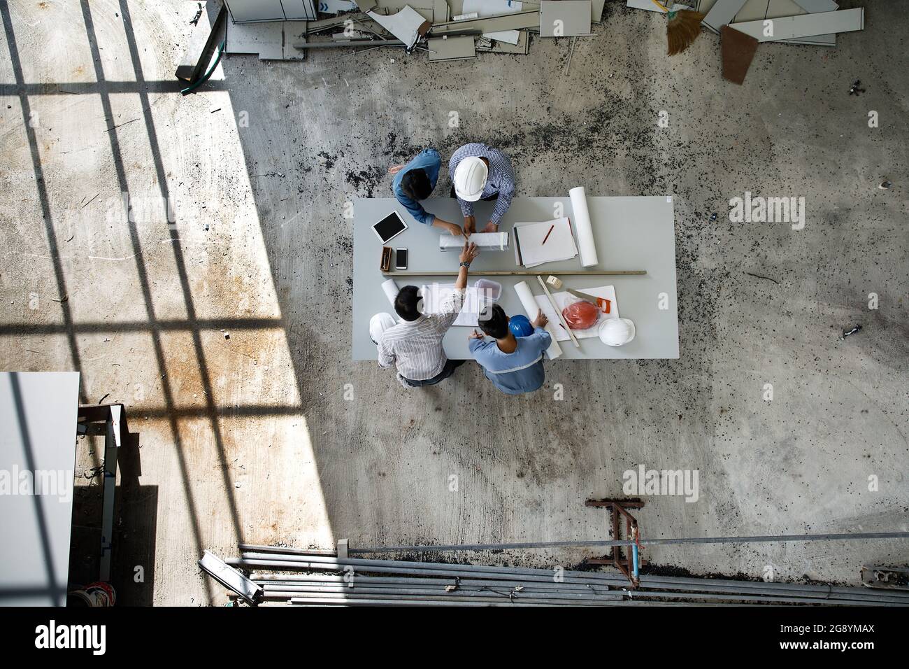 Vier Personen Team von Ingenieuren sprechen zusammen, um Baumaterial zu überprüfen, aufgenommen aus dem hohen Winkel, Draufsicht Foto Stockfoto