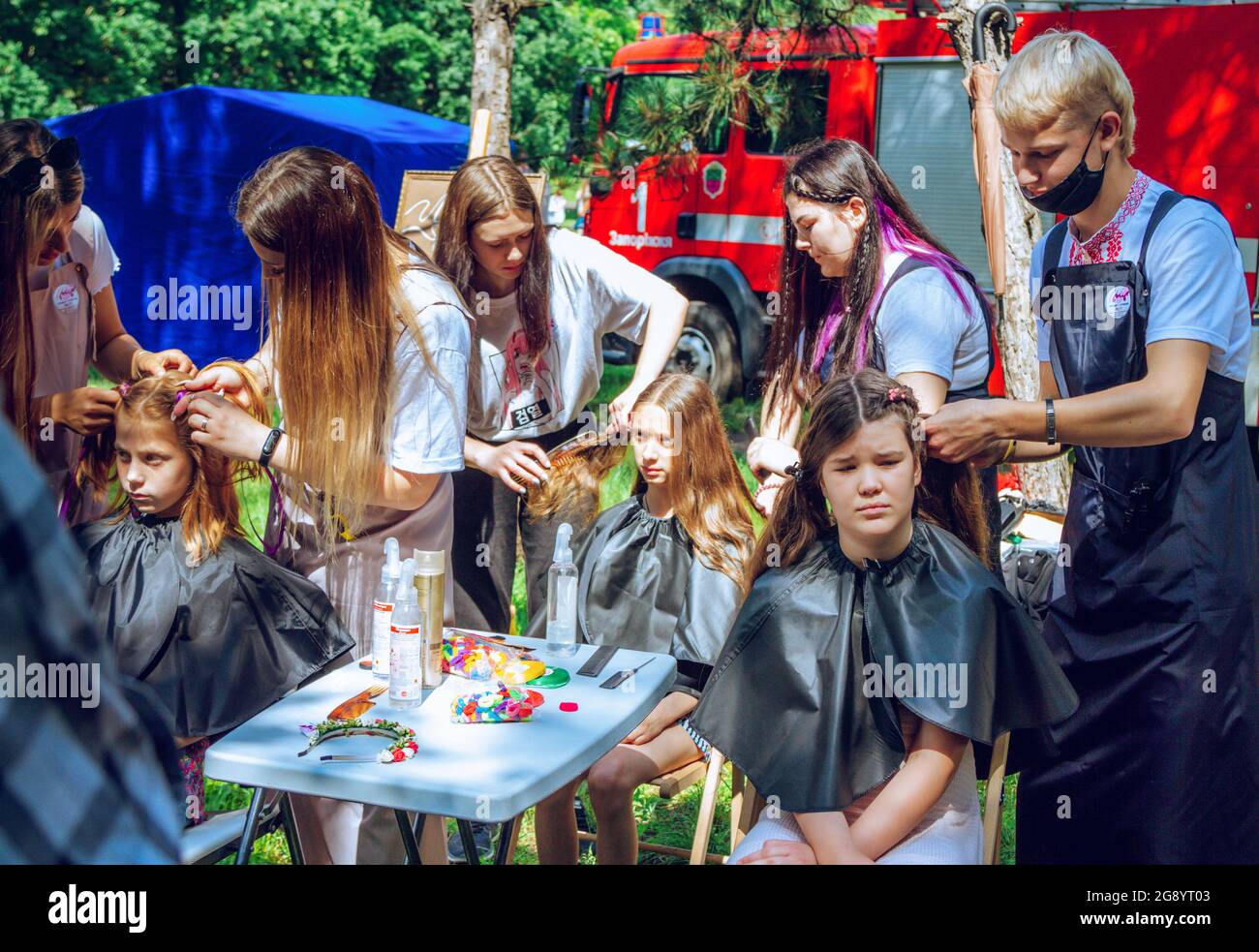 Zaporizhia, Ukraine- 19. Juni 2021: Charity Family Festival: Jungen und Mädchen nehmen an einem Outdoor-Friseurworkshop Teil. Junge Friseure bei wor Stockfoto