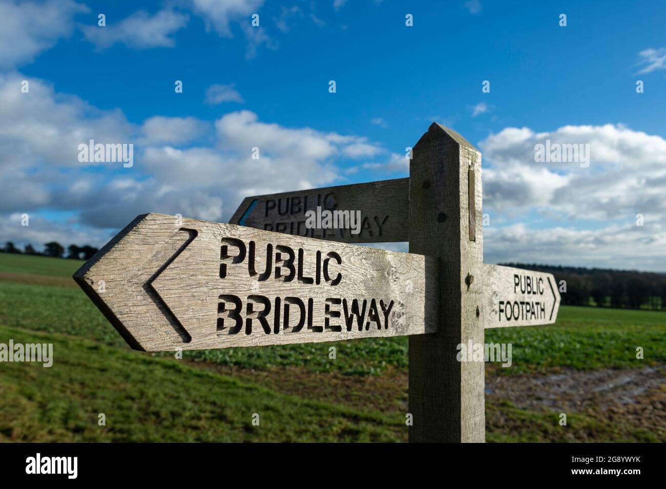 Hölzerne öffentliche Brücke Zeichen in der Landschaft mit blauem Himmel und Feldern. Stockfoto