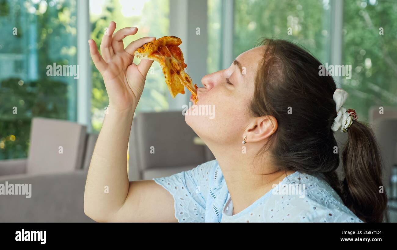 Frau nimmt ein Stück Pizza und isst gerne aus nächster Nähe Stockfoto