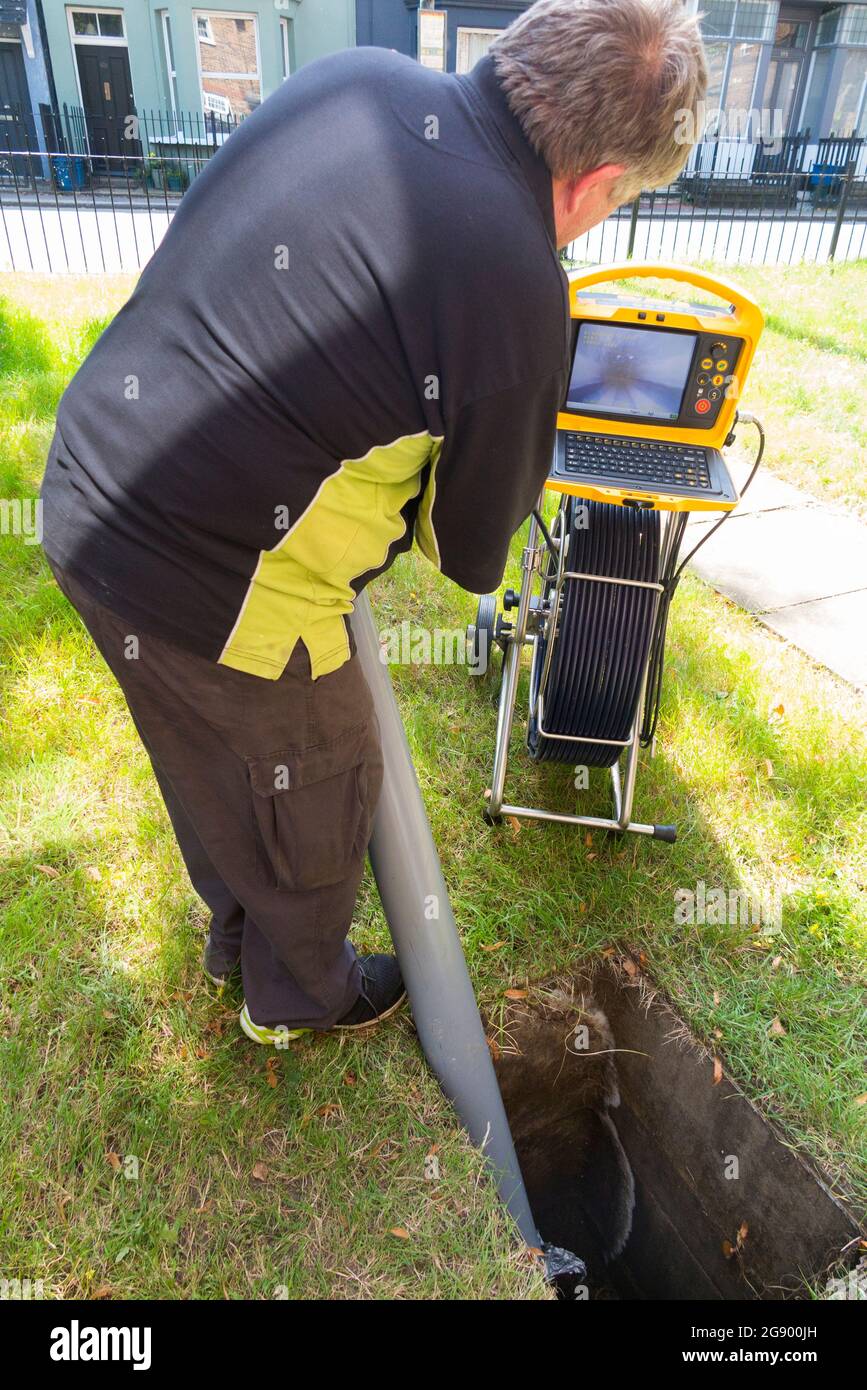 Fremdfirmen, die mit einer Kamera und einer Rolle Glasfaserkabel arbeiten, untersuchen ein verstopftes Kanalablasssystem auf Verstopfung und die Ursache des Problems. VEREINIGTES KÖNIGREICH. (127) Stockfoto