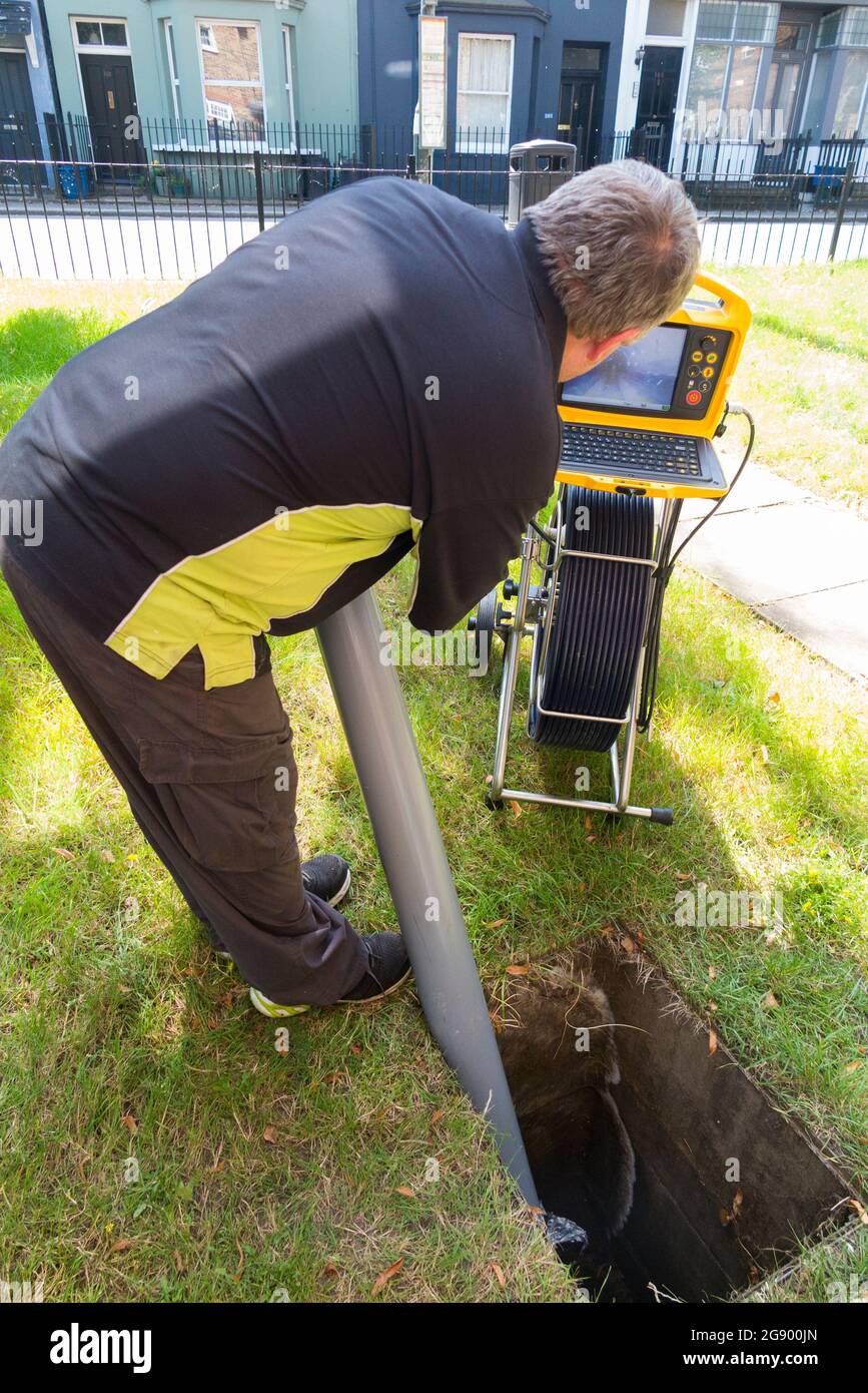 Fremdfirmen, die mit einer Kamera und einer Rolle Glasfaserkabel arbeiten, untersuchen ein verstopftes Kanalablasssystem auf Verstopfung und die Ursache des Problems. VEREINIGTES KÖNIGREICH. (127) Stockfoto