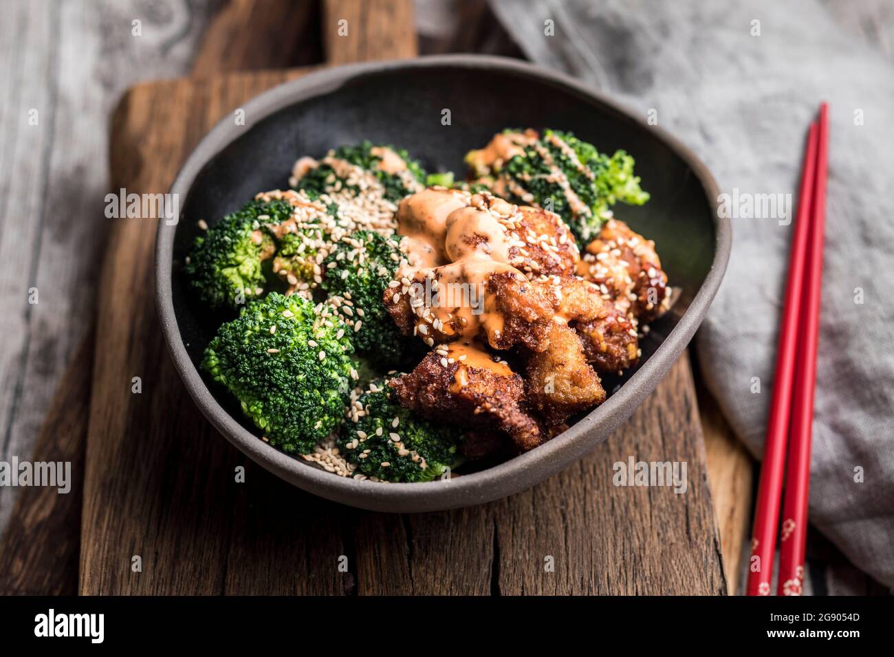 Sesam gebratenes Huhn mit Brokkoli, garniert mit sriracha-Sauce in einer Schüssel Stockfoto