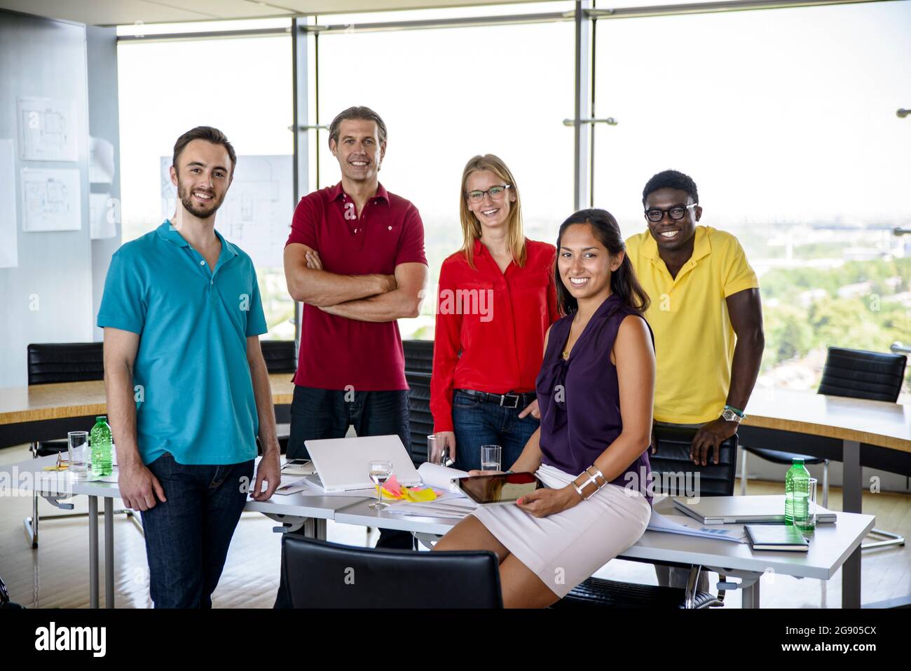 Lächelnde männliche und weibliche Profis stehen im Büro Stockfoto
