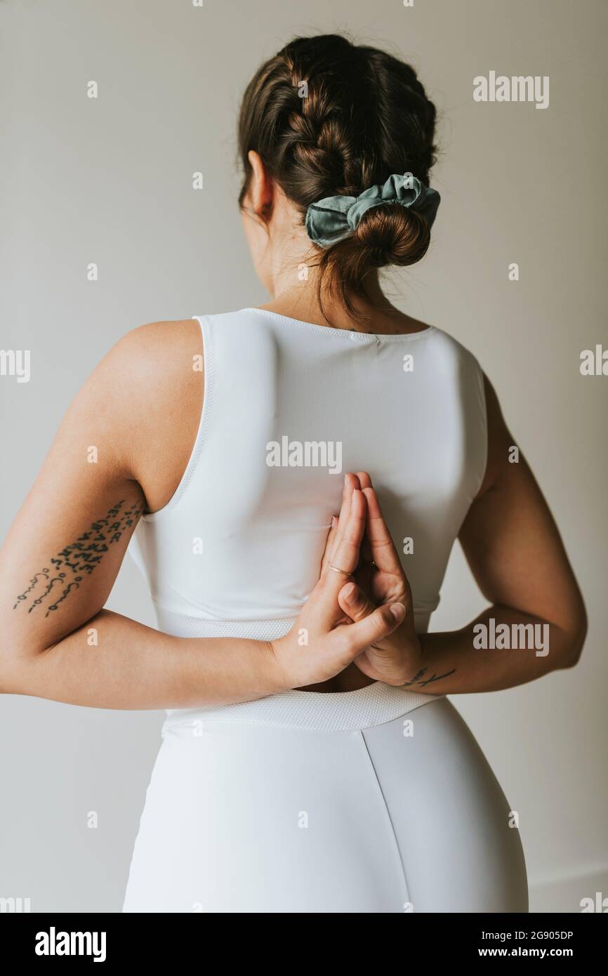 Weibliche Fitness-Ausbilderin mit den Händen hinter dem Rücken geklammert und Yoga im Health Club Stockfoto