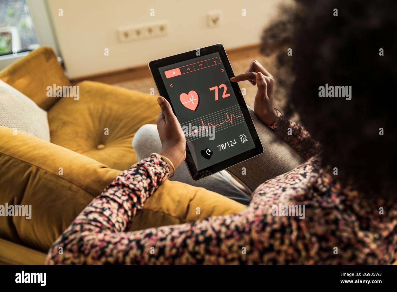 Frau, die zu Hause die Pulskurve auf einem digitalen Tablet überprüft Stockfoto