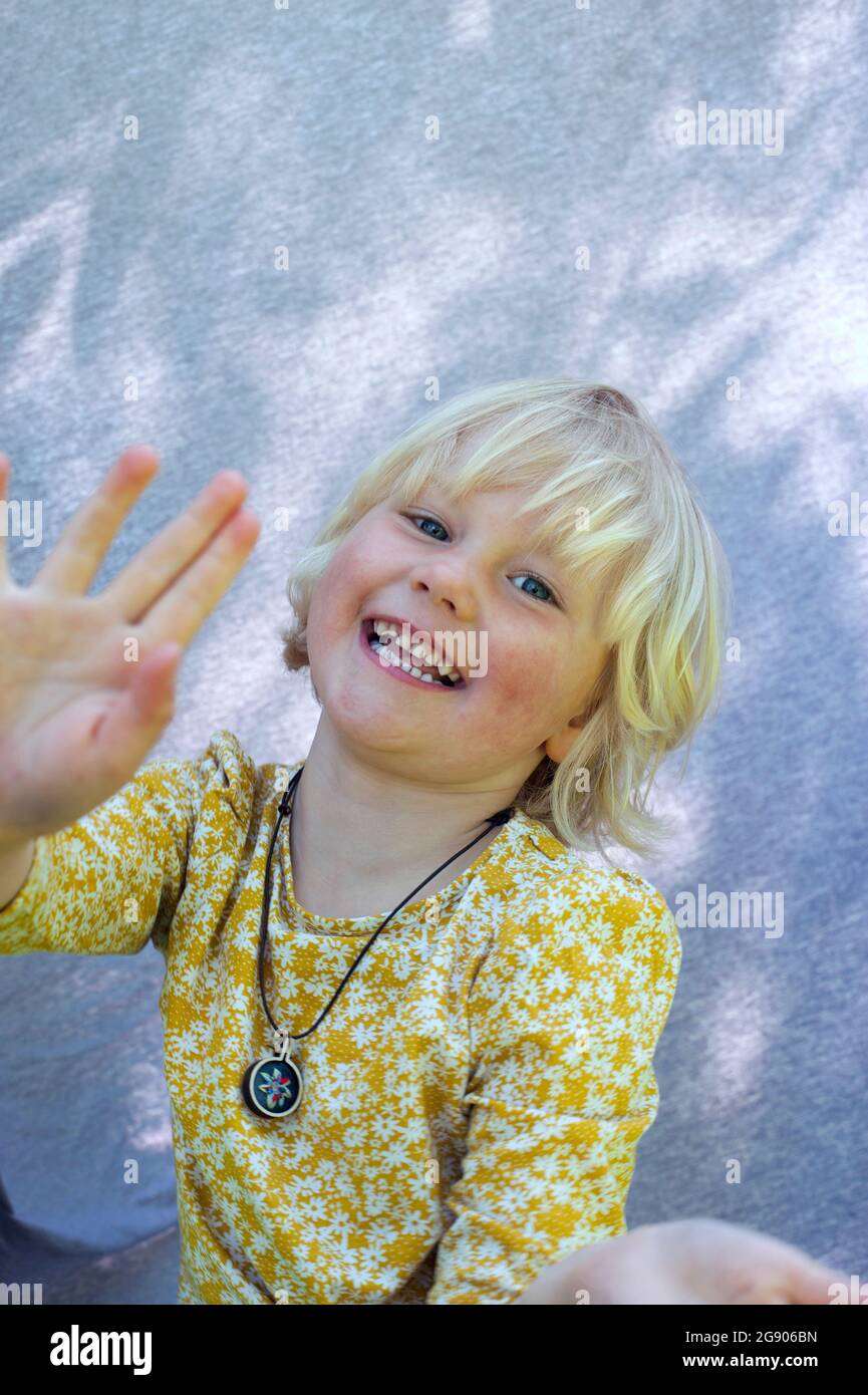 Nettes glückliches Mädchen mit blonden Haaren winkende Hand Stockfoto
