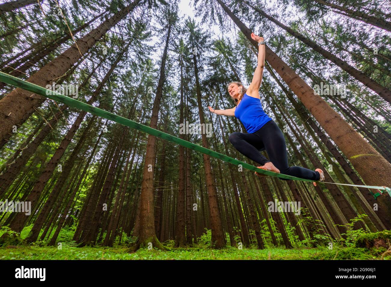 Junge Frau balanciert auf Slackline im Wald Stockfoto