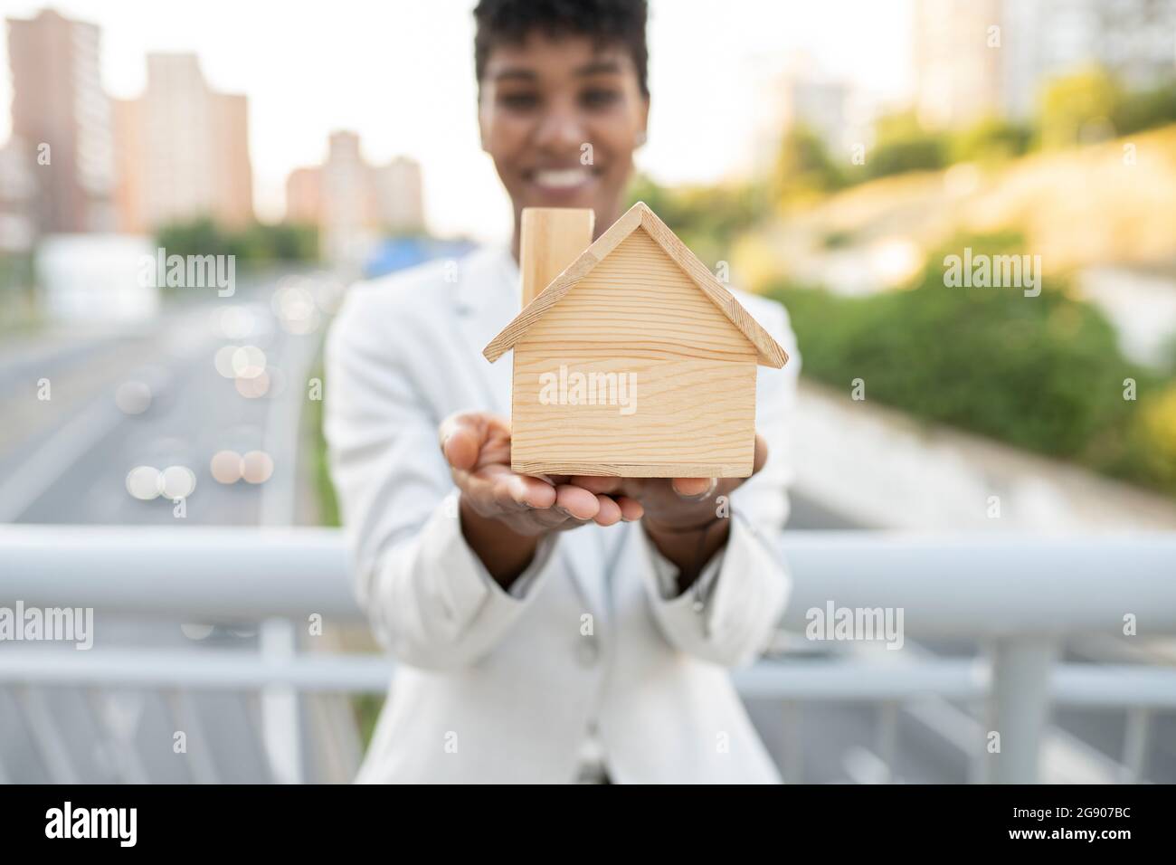 Weibliche Immobilienmaklerin mit Holzmodell nach Hause Stockfoto