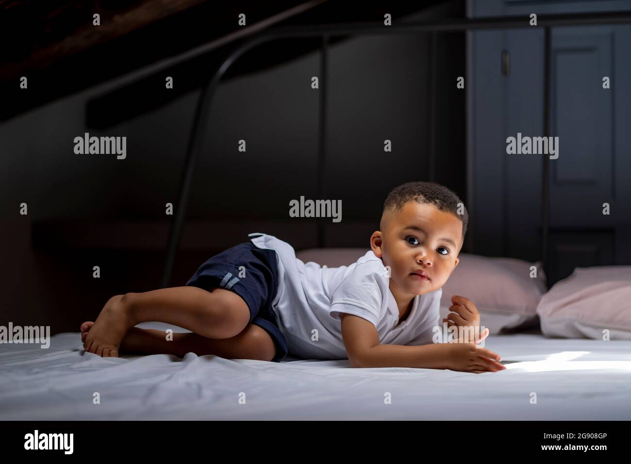 Junge, der zu Hause auf dem Dachboden auf dem Bett liegt Stockfoto