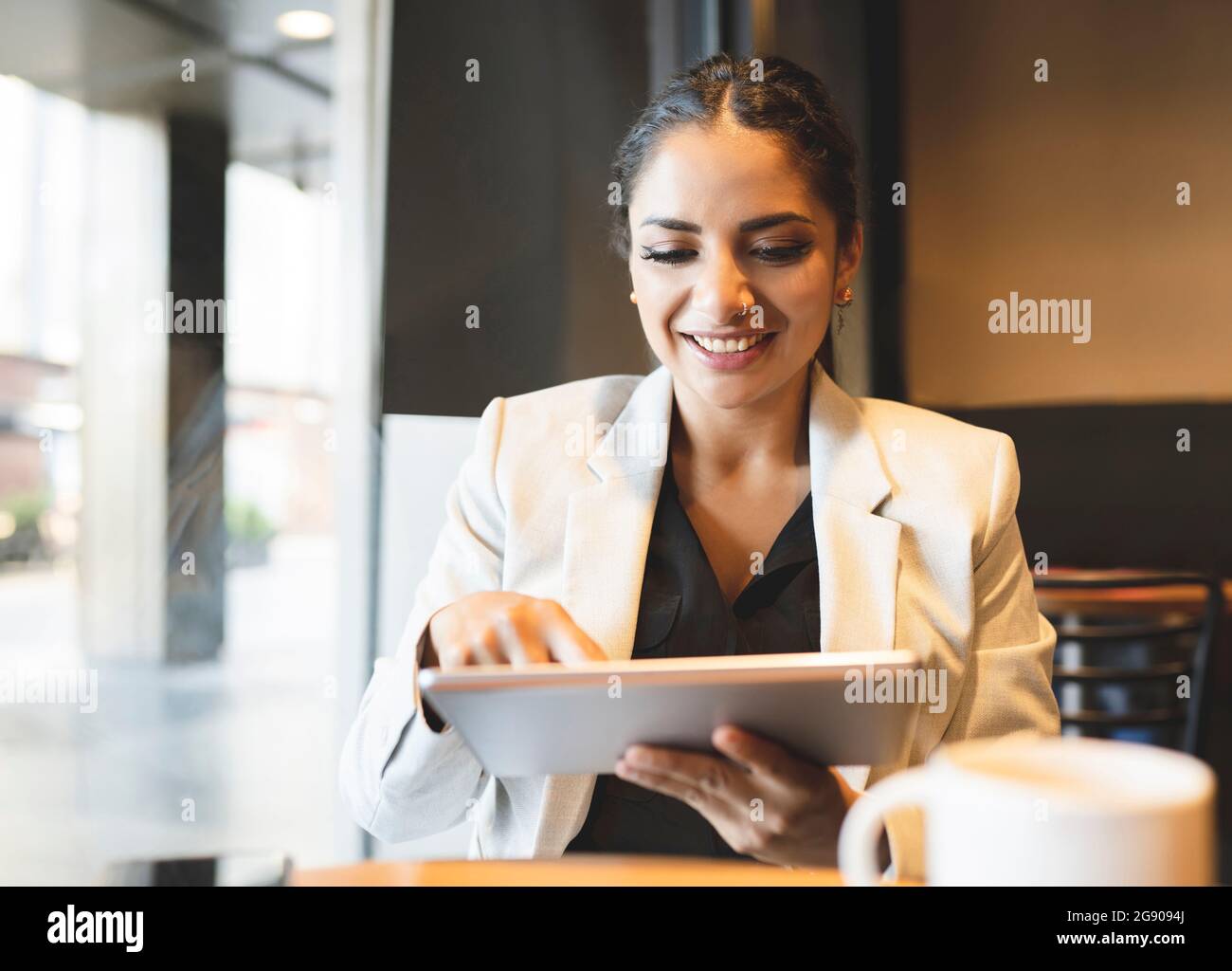 Weibliche Profikerin, die ein digitales Tablet benutzt, während sie im Café sitzt Stockfoto
