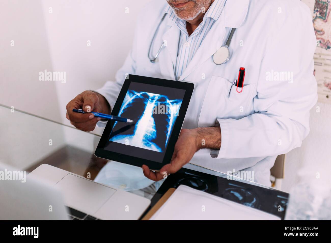 Leitender Arzt erklärt Röntgenaufnahmen auf einem digitalen Tablet im Krankenhaus Stockfoto