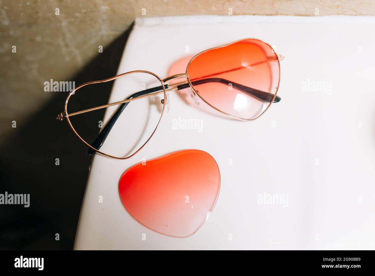 Gebrochene orangefarbene herzförmige Sonnenbrille auf dem Tisch Stockfoto