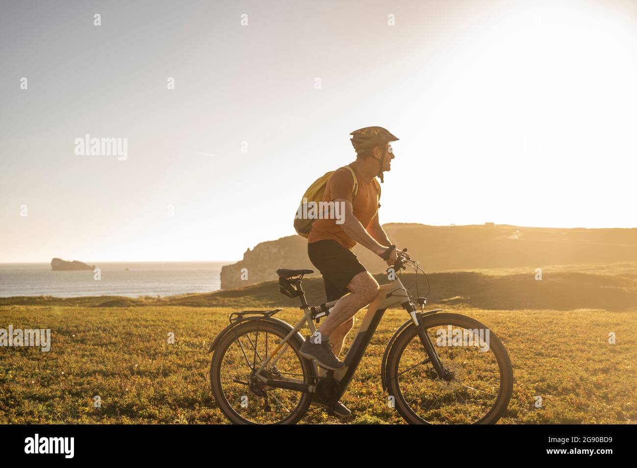 Männlicher Athlet, der auf Gras mit dem Elektro-Mountainbike fährt Stockfoto