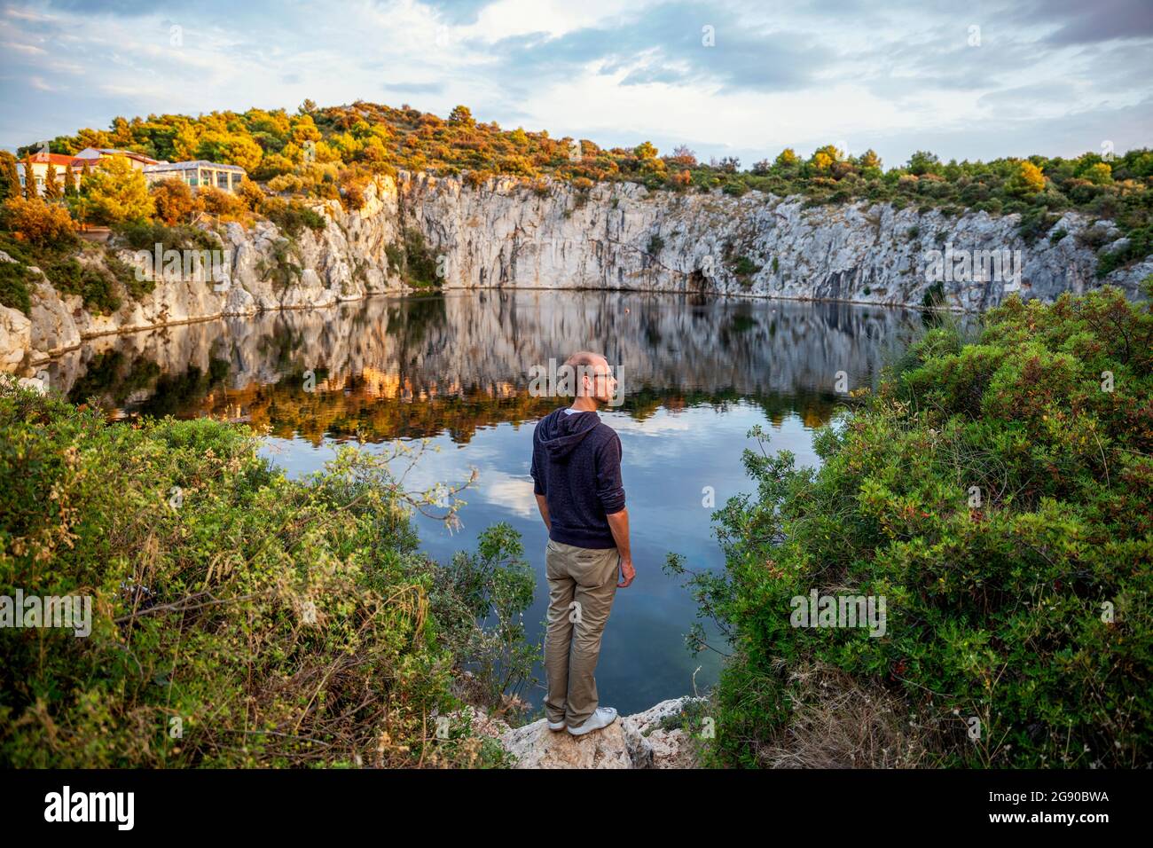 Mann, der auf einer Felsformation steht, während er das Drachenauge-See, Rogoznica, Kroatien, anschaut Stockfoto