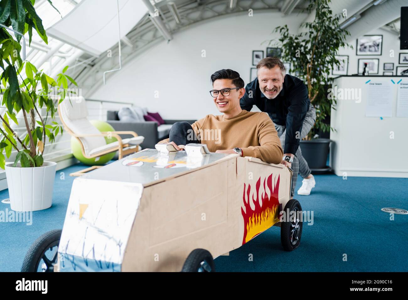 Lächelnde Kollegen, die im Büro mit dem Spielzeugauto spielen Stockfoto