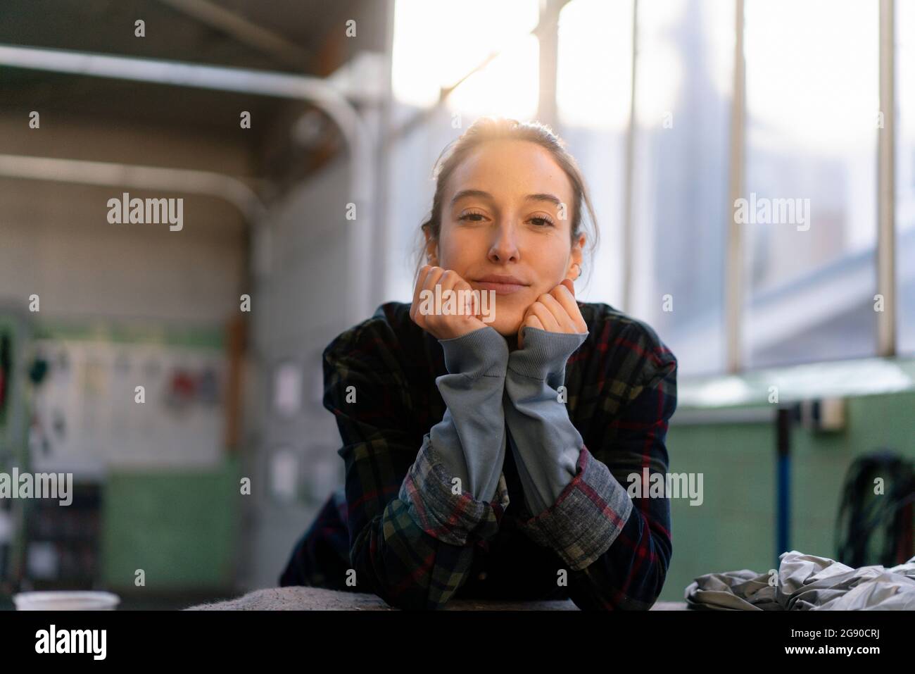 Mechanikerin mit der Hand auf dem Kinn in der Werkstatt gelehnt Stockfoto