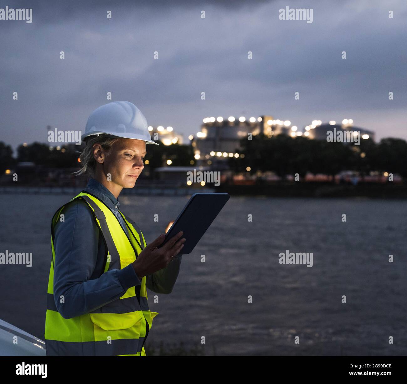 Weibliche Profi in reflektierender Kleidung mit digitalem Tablet in der Abenddämmerung Stockfoto