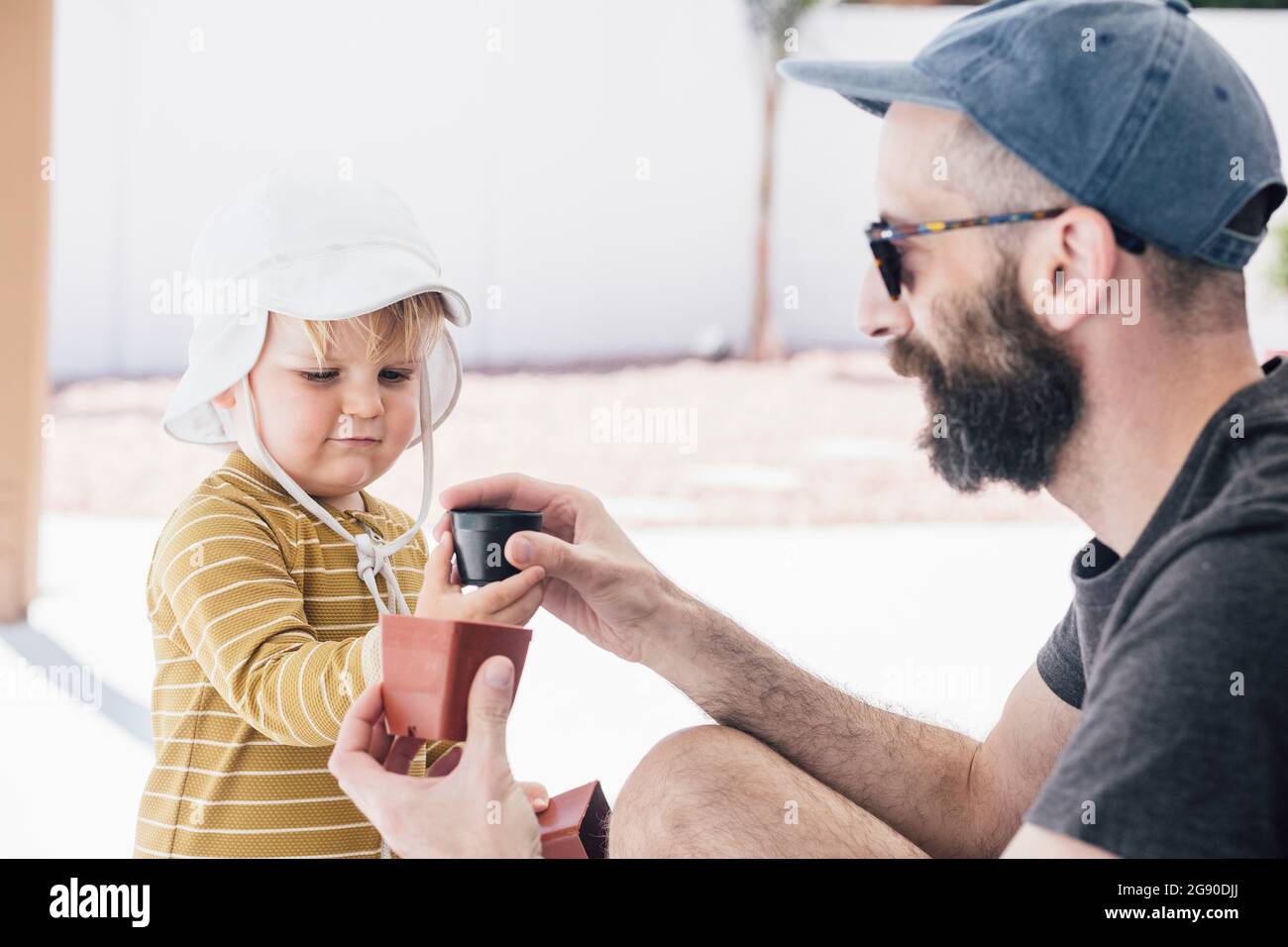 Bärtiger Mann, der während des Urlaubs am sonnigen Tag mit seinem Sohn auf der Terrasse spielte Stockfoto