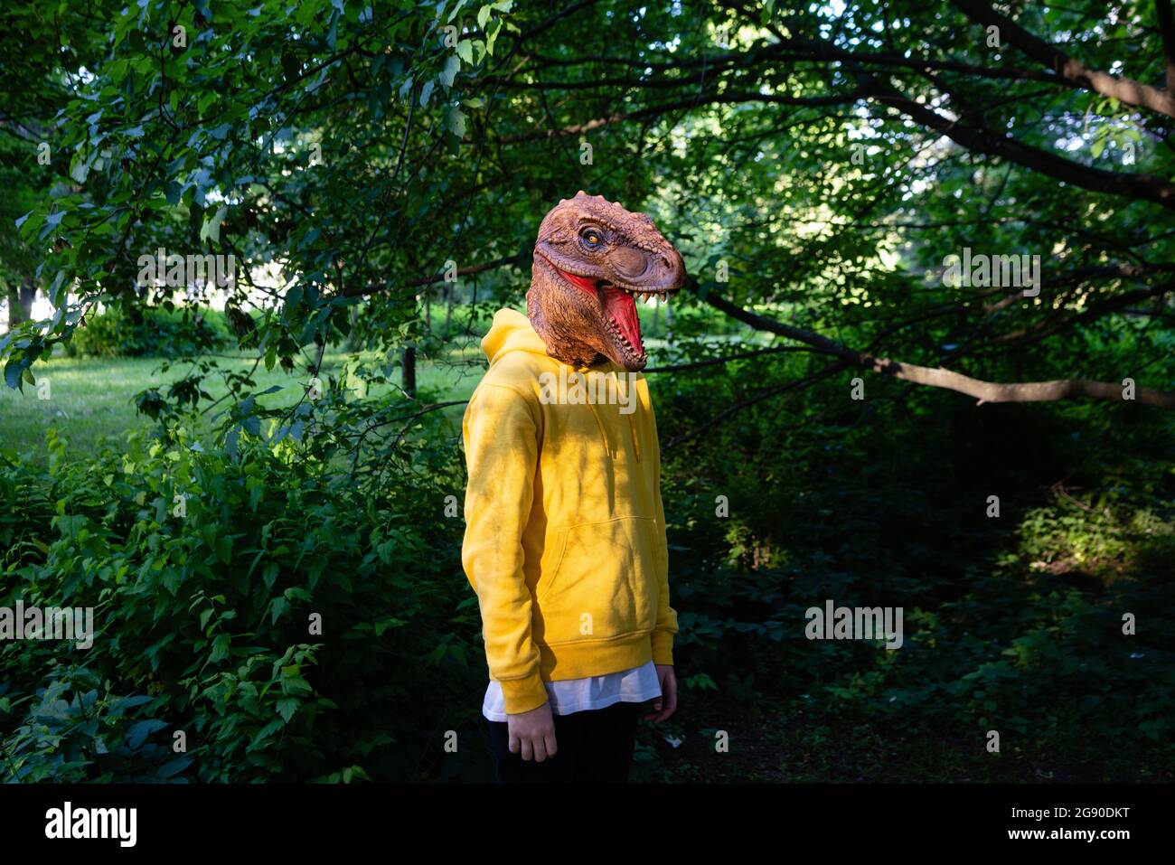 Vorpubertär Junge trägt Dinosaurier-Maske Stockfoto