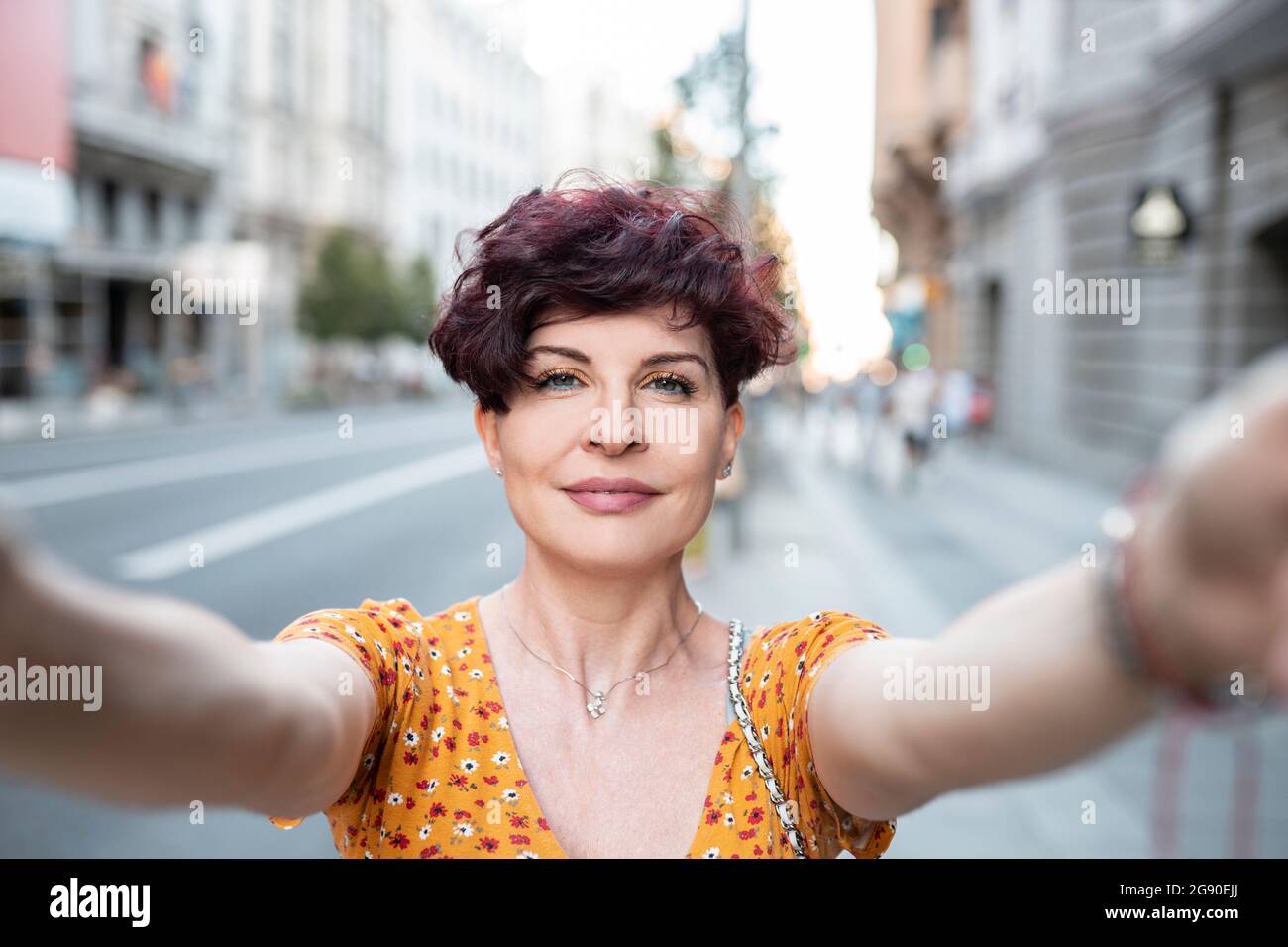 Reife Frau mit kurzen Haaren nimmt Selfie in der Stadt Stockfoto