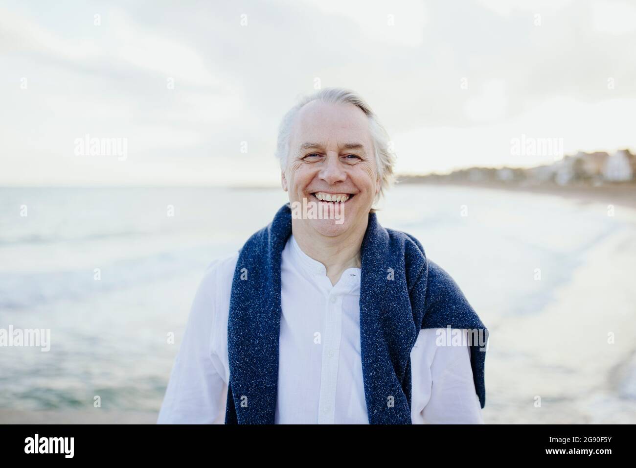 Glücklicher reifer Mann mit weißen Haaren an der Küste während des Urlaubs Stockfoto