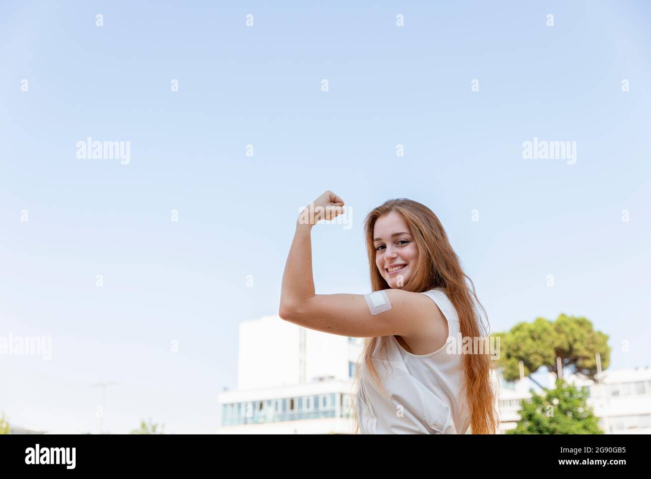 Schöne Freiberuflerin, die die Muskeln am Himmel biegend Stockfoto