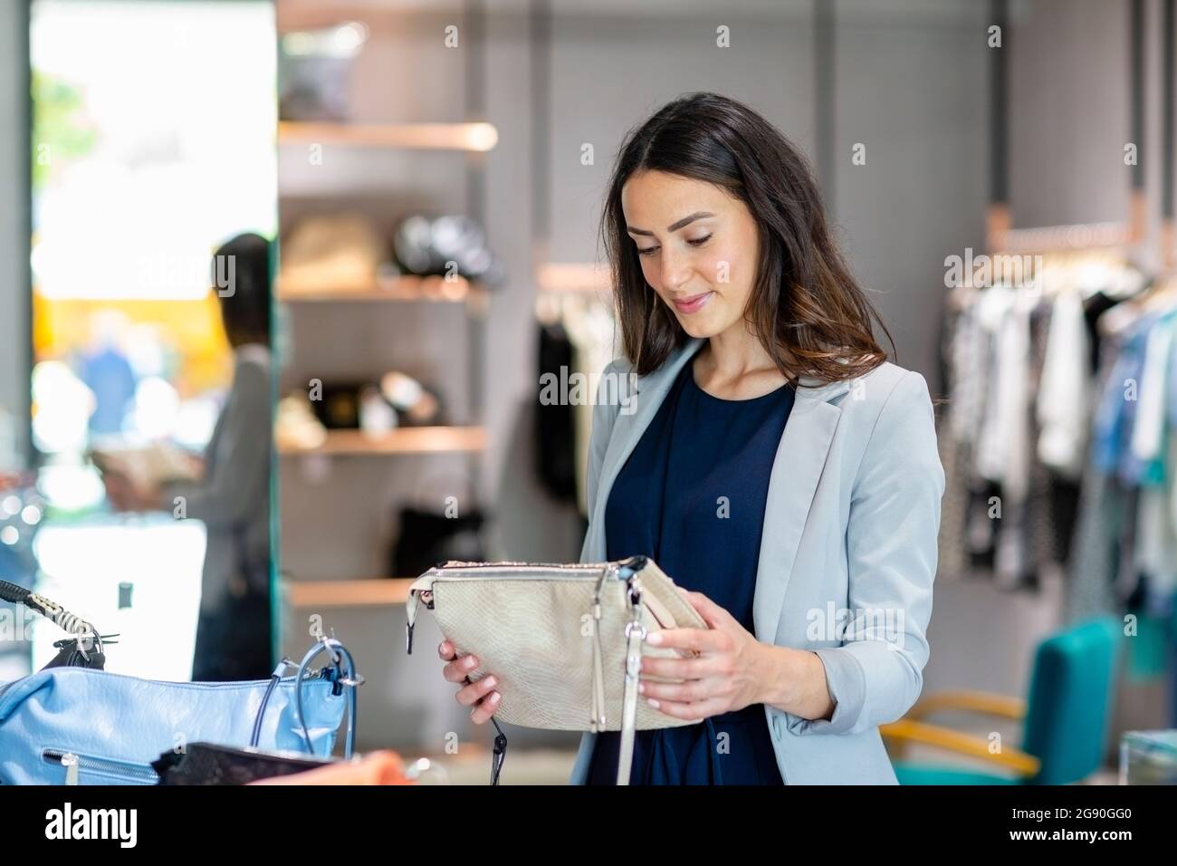 Junge Frau hält Geldbörse, während sie im Geschäft einkaufen Stockfoto