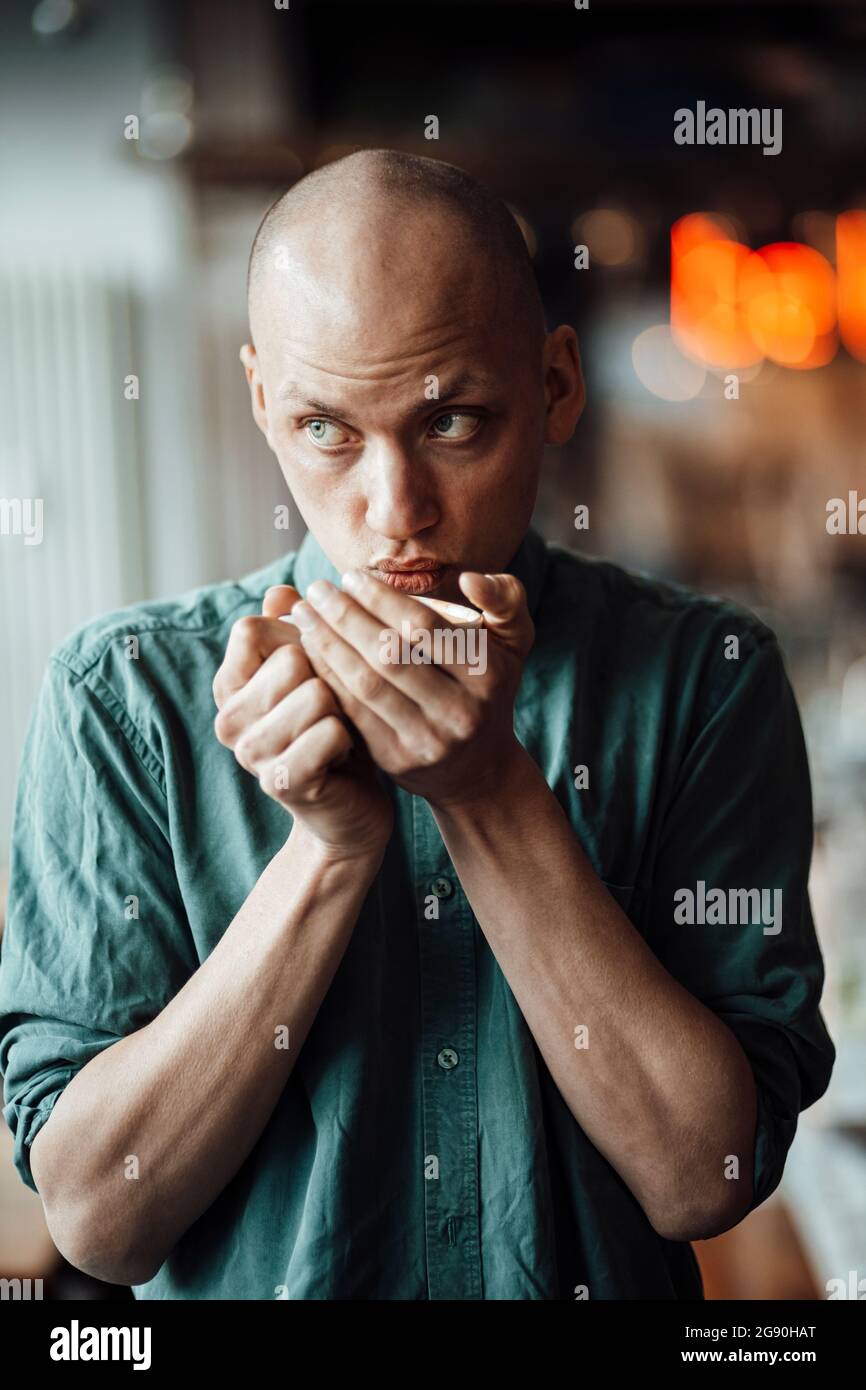 Männlicher Cafe-Besitzer schaut weg, während er Kaffee trinkt Stockfoto