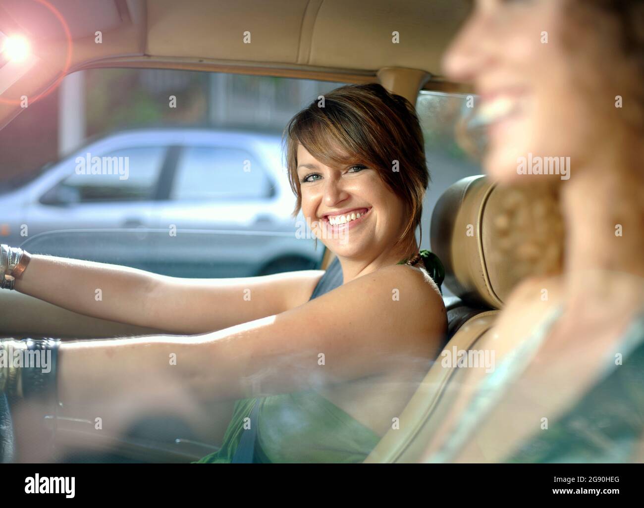 Fröhliche Frau mit Freundin, die Auto fährt Stockfoto