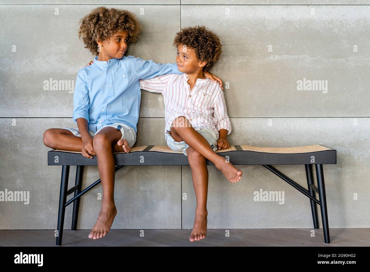 Jungen mit der Hand auf den Schultern, die sich auf der Bank angucken Stockfoto