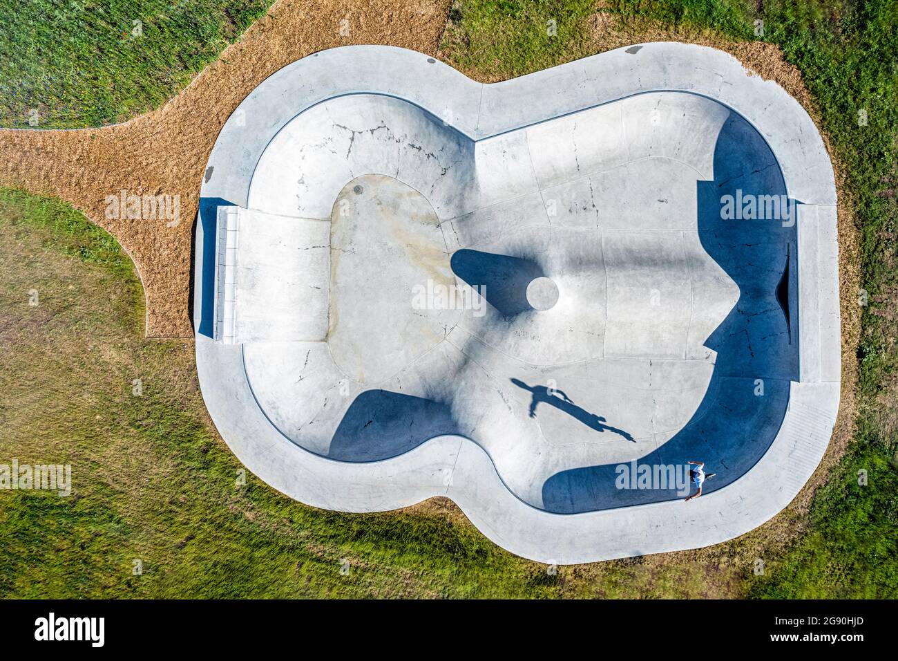 Junger Mann in Inline-Skates, der an einem sonnigen Tag über eine Sportrampe springt Stockfoto