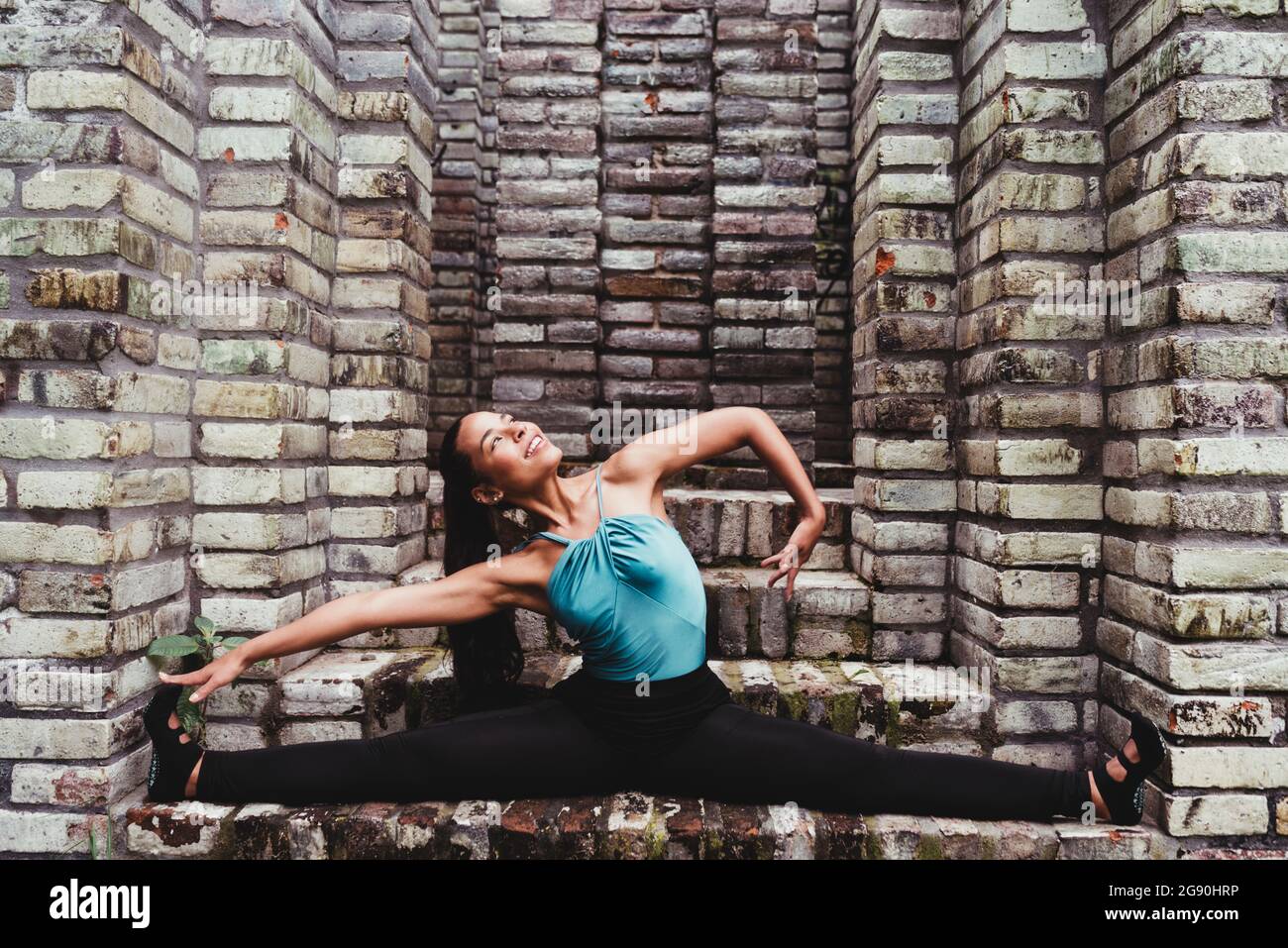 Lächelnde Frau, die Yoga in Steinstruktur praktiziert Stockfoto