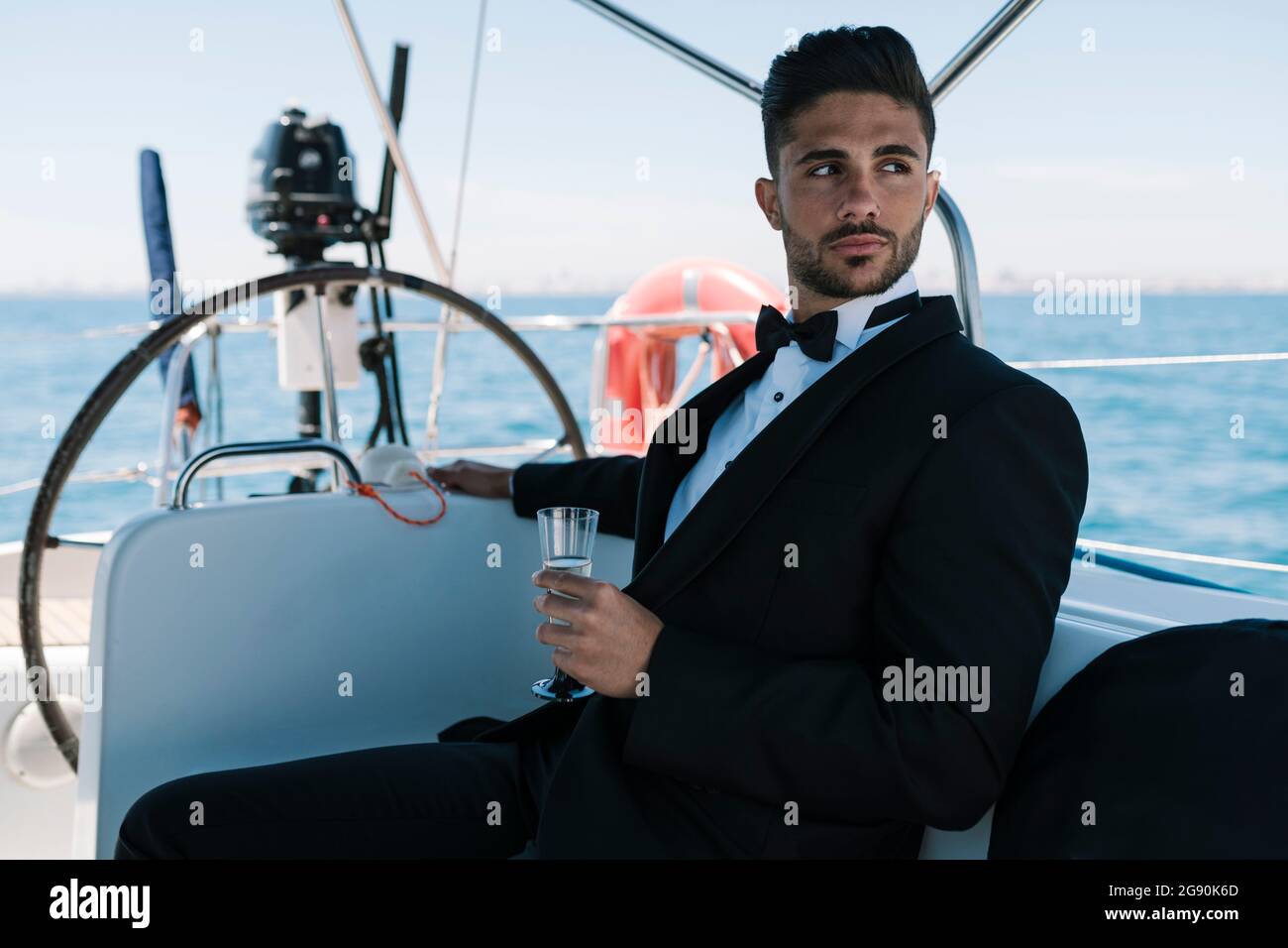 Junger Mann mit einem Getränk, der während des Urlaubs auf einer Yacht unterwegs war Stockfoto