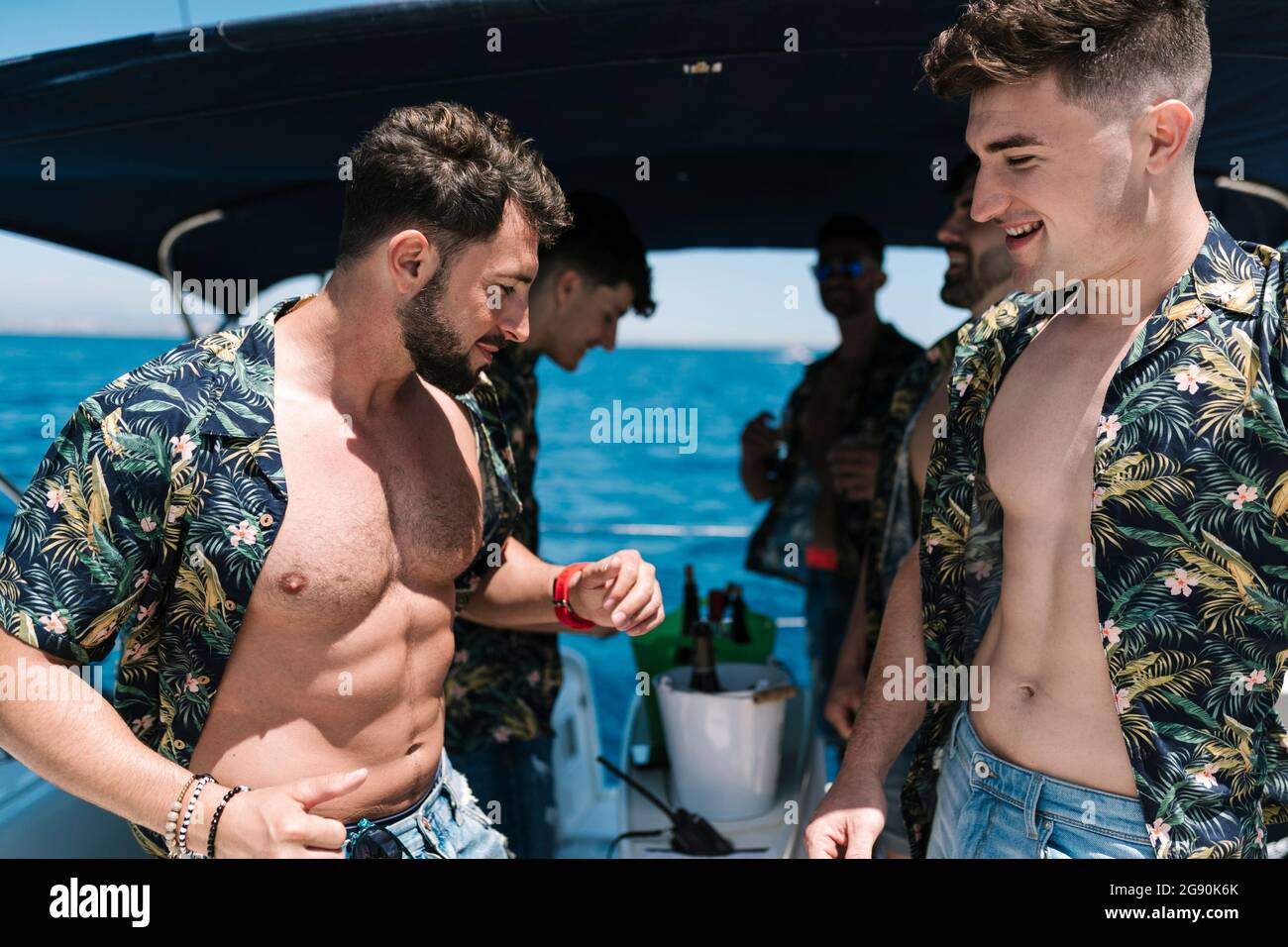 Bärtiger Mann, der während des Urlaubs mit männlichen Freunden auf der Yacht tanzt Stockfoto