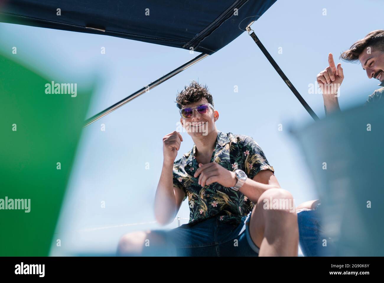 Lächelnder, hübscher junger Mann mit Freund auf der Yacht während des Urlaubs Stockfoto