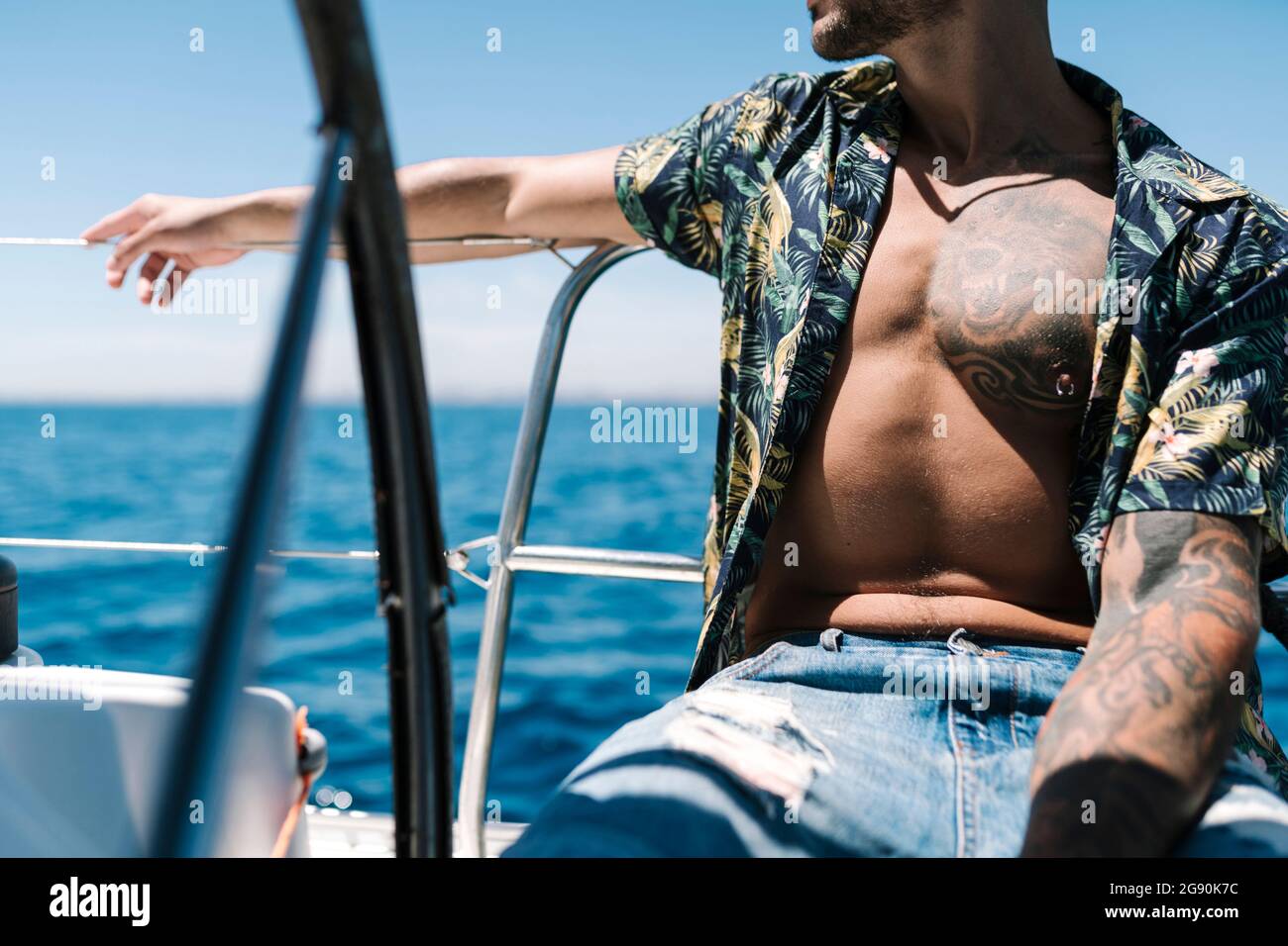 Hipster-Mann mit unknöpfbarem Hemd sitzt an sonnigen Tagen auf der Yacht Stockfoto