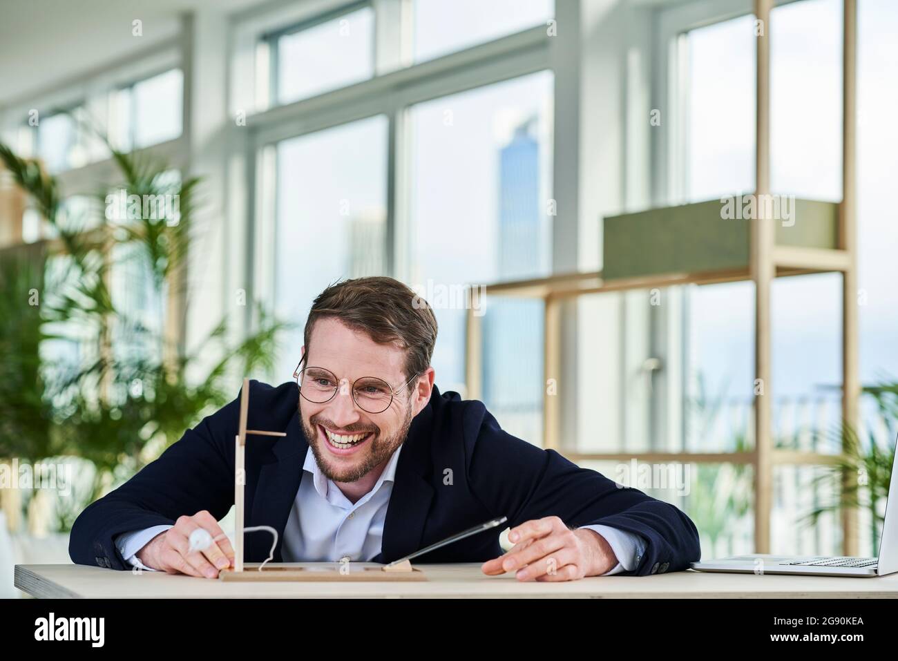 Fröhlicher Geschäftsmann, der von zu Hause aus ein Architekturmodell ansieht Stockfoto