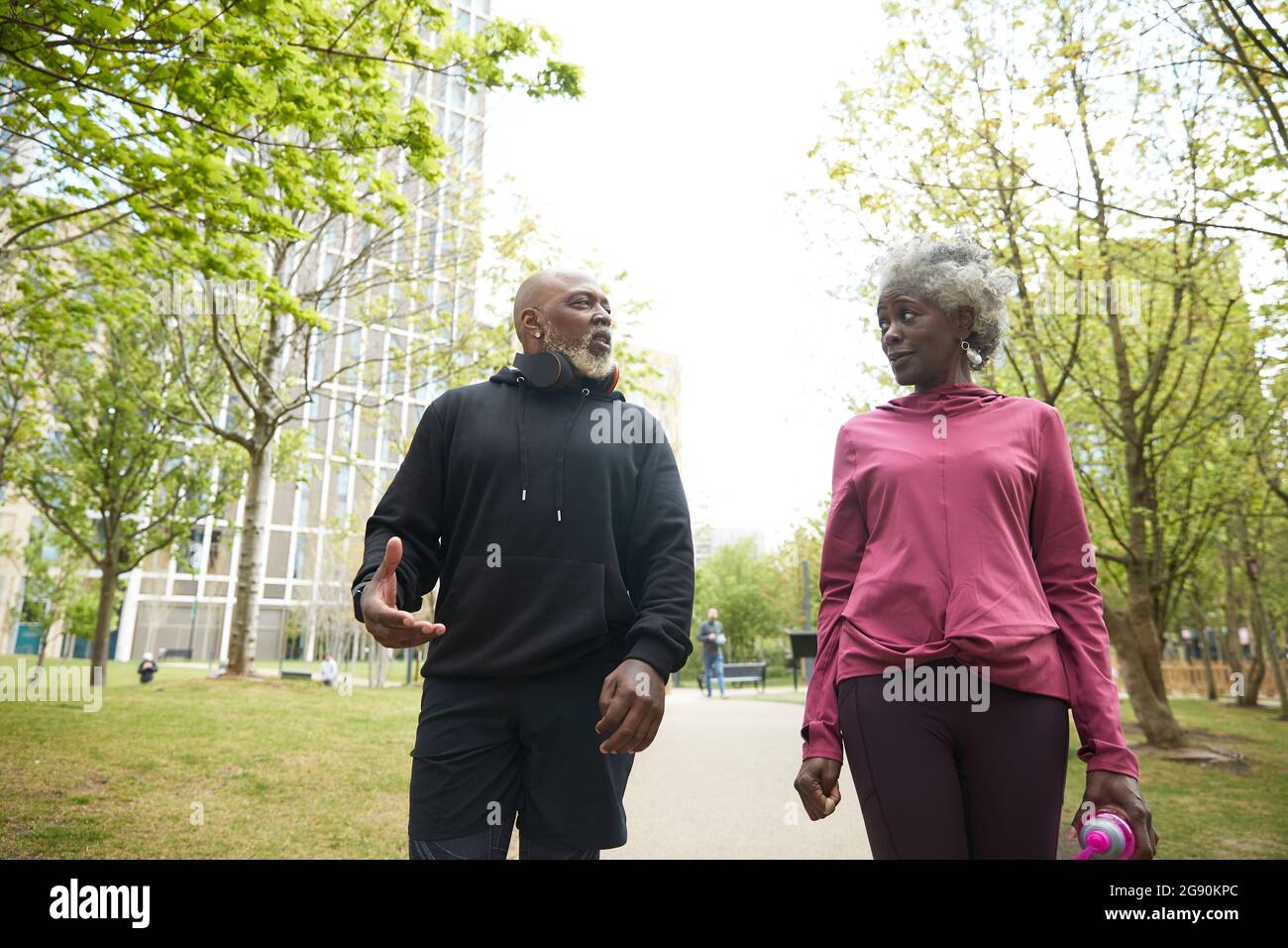 Mann, der mit einer älteren Frau spricht, die im öffentlichen Park läuft Stockfoto