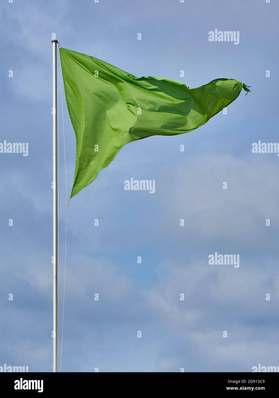 Eine dreieckige grüne Flagge über einem wolkigen Himmel. Stockfoto