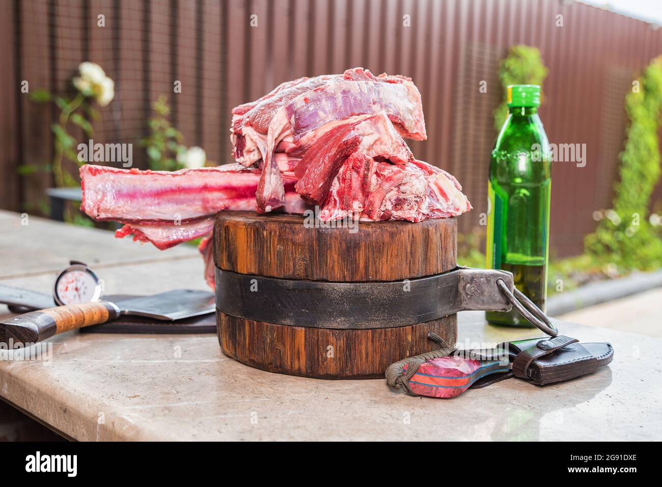 Rohes Fleisch auf einer Terrasse für das Mittagessen. Frisches Fleisch auf einem Schneidebrett mit Olivenöl und einem Messer. Nahaufnahme. Stockfoto