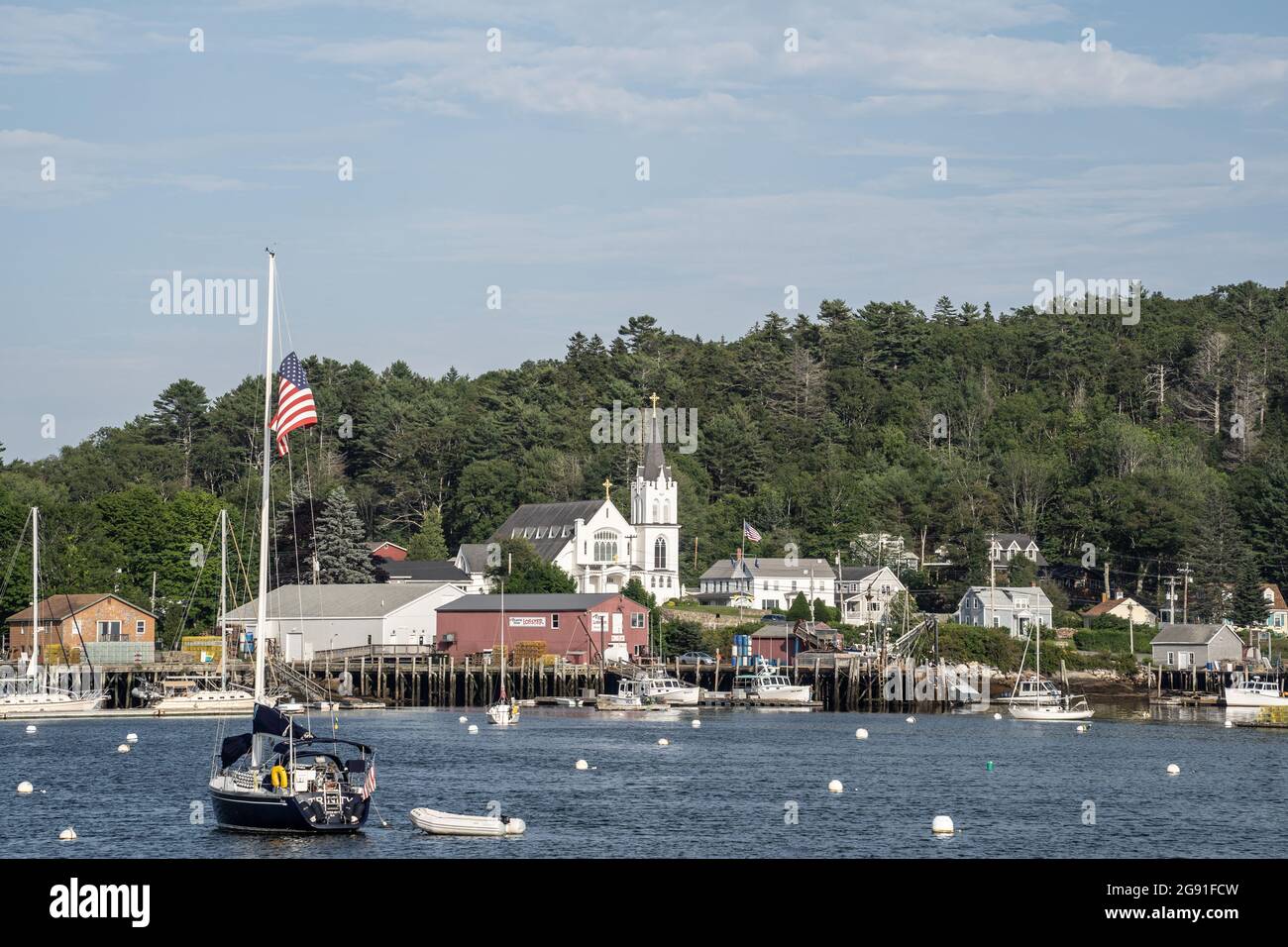 Boothbay, Maine, USA-12. Juli 2021: Katholische Kirche der Muttergottes des Friedens am Ufer des Boothbay Harbor, Maine. Hummer- und Fischerboote liegen im Harbo Stockfoto