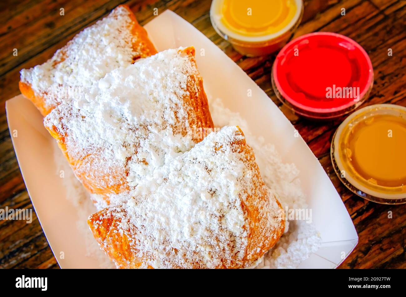 Beignets werden in Mo’ Bay Beignet Co., 23. Juli 2021, in Mobile, Alabama, mit Buttercreme, Himbeere und Zimt-Dipping-Sirup serviert. Stockfoto